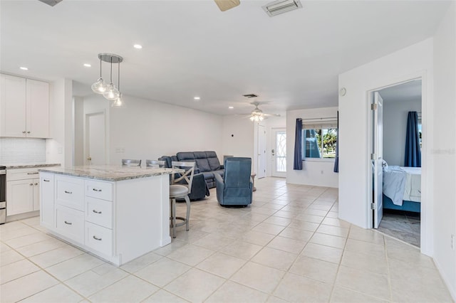 kitchen with tasteful backsplash, open floor plan, visible vents, a kitchen bar, and ceiling fan