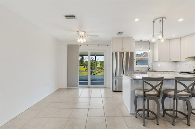 kitchen with appliances with stainless steel finishes, decorative backsplash, a sink, and visible vents