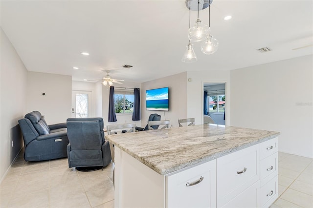 kitchen with light tile patterned floors, ceiling fan, white cabinets, open floor plan, and decorative light fixtures