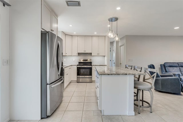 kitchen featuring visible vents, a kitchen island, a breakfast bar, appliances with stainless steel finishes, and open floor plan