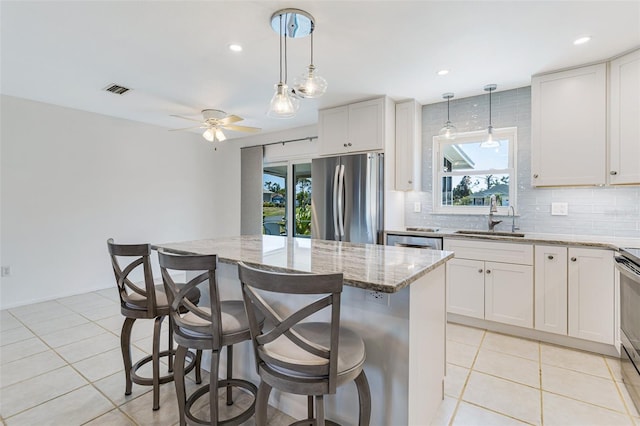 kitchen with appliances with stainless steel finishes, decorative backsplash, a sink, and light stone countertops