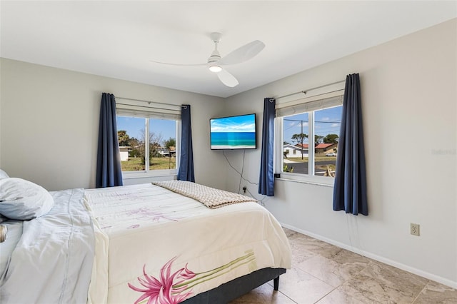 bedroom featuring baseboards, marble finish floor, multiple windows, and a ceiling fan