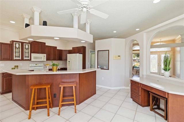 201 Bayside Ct, Nokomis, FL 34275 - kitchen featuring a kitchen breakfast bar, light countertops, white appliances, arched walkways, and glass insert cabinets