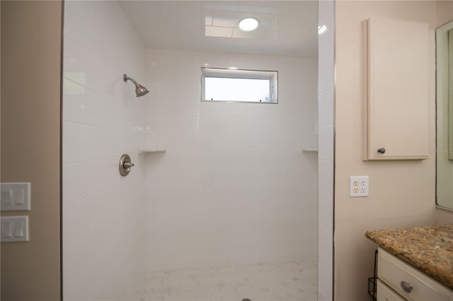 bathroom with vanity and a tile shower