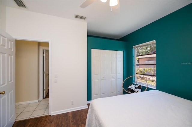 bedroom with baseboards, visible vents, wood finished floors, and a closet