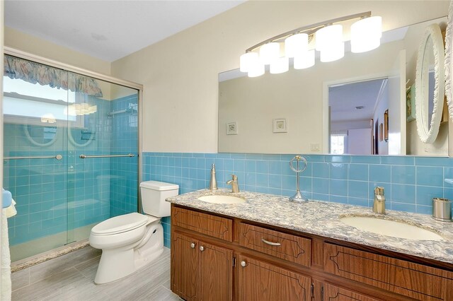 810 Anchorage Ln, Palm Harbor, FL 34685 - full bath featuring toilet, tile walls, double vanity, a shower stall, and wainscoting
