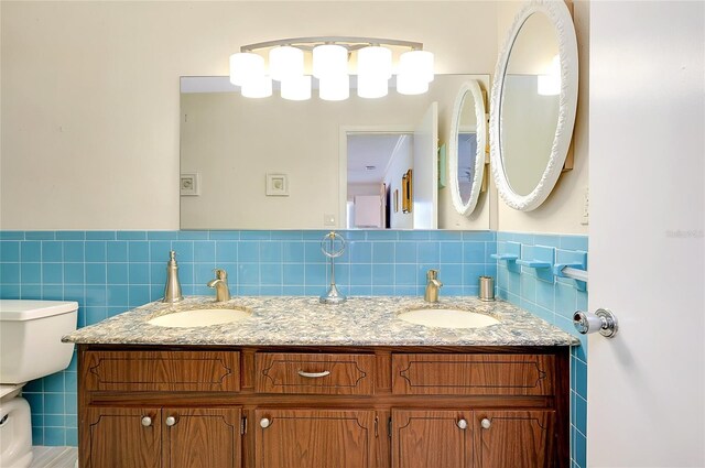 810 Anchorage Ln, Palm Harbor, FL 34685 - bathroom with tile walls, double vanity, toilet, and a wainscoted wall