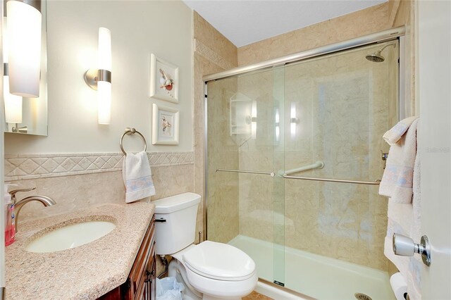 810 Anchorage Ln, Palm Harbor, FL 34685 - full bathroom featuring tile walls, vanity, a shower stall, toilet, and a wainscoted wall