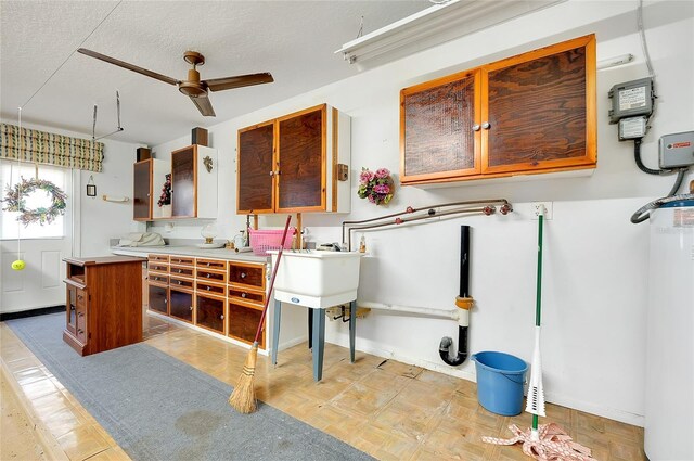 810 Anchorage Ln, Palm Harbor, FL 34685 - kitchen featuring ceiling fan, water heater, a textured ceiling, light countertops, and brown cabinets