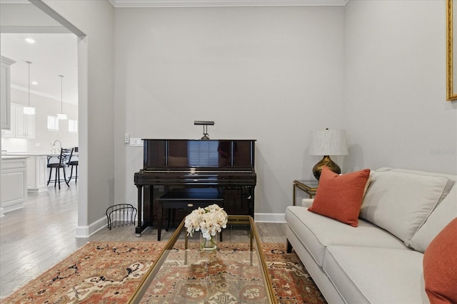 living area with light wood-type flooring, crown molding, and baseboards