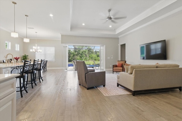 living area with baseboards, ornamental molding, recessed lighting, light wood-style flooring, and ceiling fan with notable chandelier