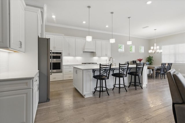 kitchen with white cabinets, an inviting chandelier, light countertops, stainless steel appliances, and a breakfast bar area