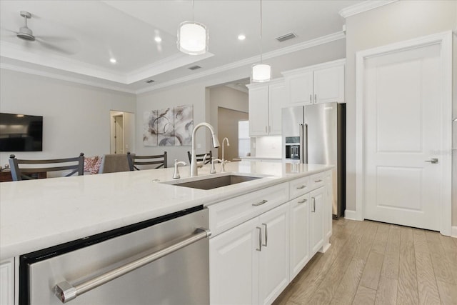 kitchen featuring visible vents, a sink, ornamental molding, light countertops, and appliances with stainless steel finishes