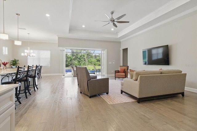 living room with light wood-style floors, ceiling fan with notable chandelier, baseboards, and a wealth of natural light