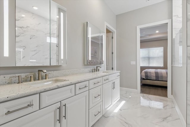 bathroom with double vanity, marble finish floor, a sink, and baseboards