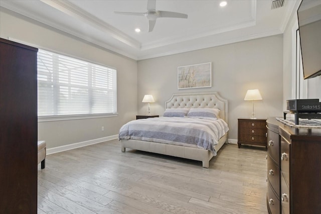bedroom featuring ornamental molding, light wood-style flooring, and a raised ceiling
