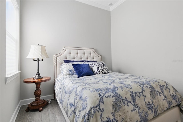 bedroom with crown molding, baseboards, and wood finished floors
