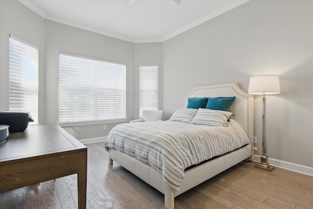 bedroom with baseboards, ornamental molding, and wood finished floors
