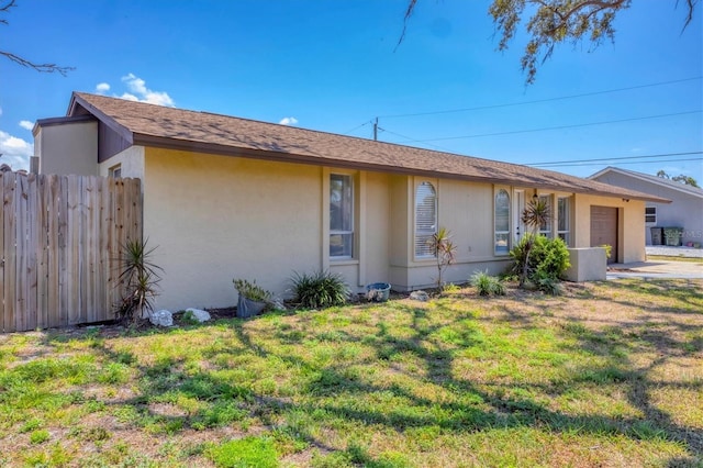 5755 Oxalis Rd, Venice, FL 34293 - ranch-style home with stucco siding, a garage, a front lawn, and fence