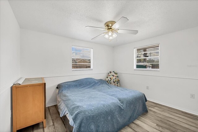 5755 Oxalis Rd, Venice, FL 34293 - bedroom featuring baseboards, multiple windows, wood finished floors, and a textured ceiling
