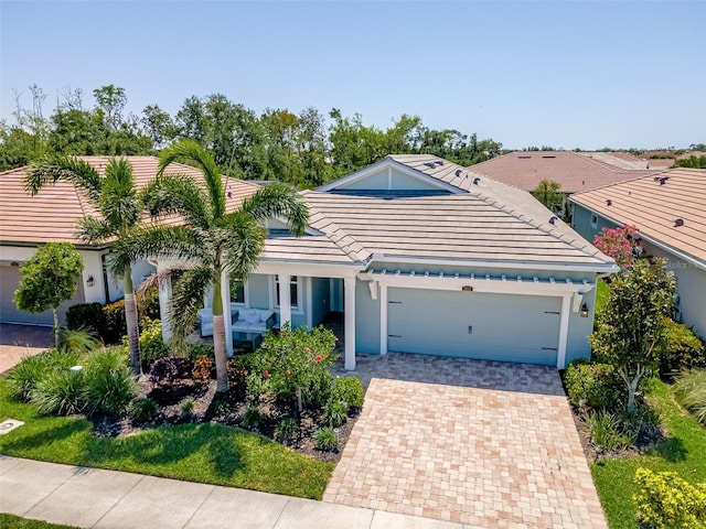 view of front of property featuring a garage, stucco siding, a tile roof, and decorative driveway