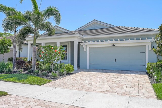 ranch-style home featuring an attached garage, stucco siding, and decorative driveway