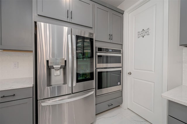 kitchen featuring gray cabinets, light stone countertops, marble finish floor, and stainless steel appliances