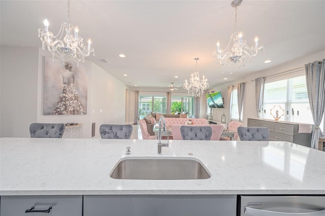 kitchen with a notable chandelier, a sink, open floor plan, recessed lighting, and stainless steel dishwasher