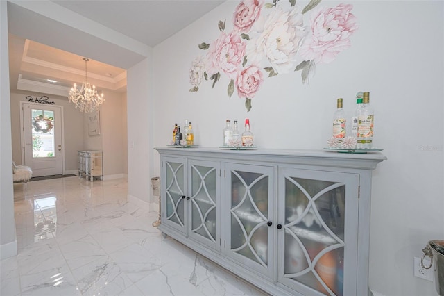 interior space featuring crown molding, an inviting chandelier, a tray ceiling, marble finish floor, and baseboards