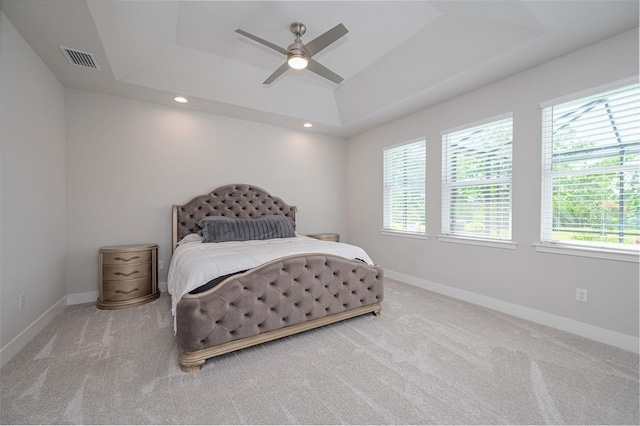 bedroom with carpet flooring, visible vents, multiple windows, and a raised ceiling