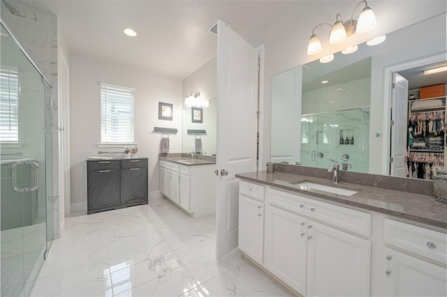 full bathroom with marble finish floor, two vanities, a marble finish shower, and a sink