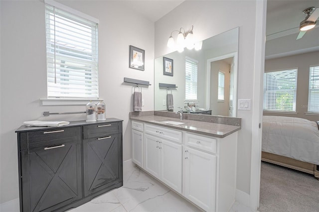 ensuite bathroom with two vanities, connected bathroom, ceiling fan, marble finish floor, and a sink