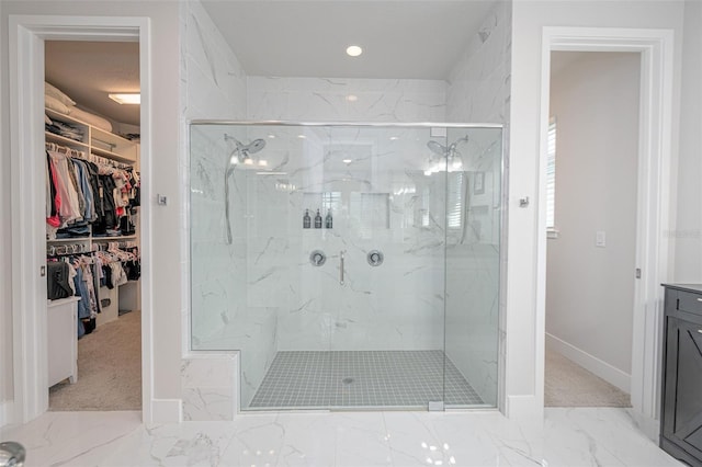 bathroom featuring marble finish floor, baseboards, a walk in closet, and a marble finish shower