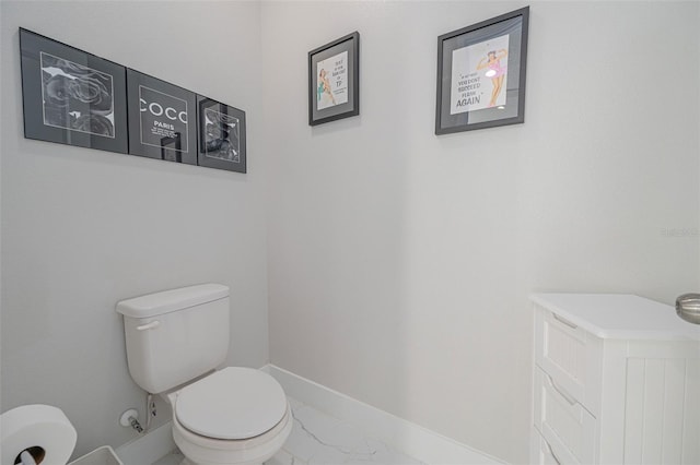 bathroom with marble finish floor, baseboards, and toilet