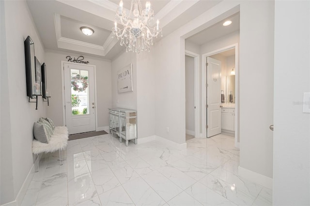 interior space with a notable chandelier, baseboards, crown molding, and a raised ceiling