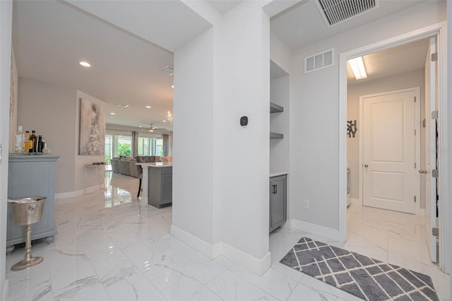 hallway with marble finish floor, baseboards, and visible vents