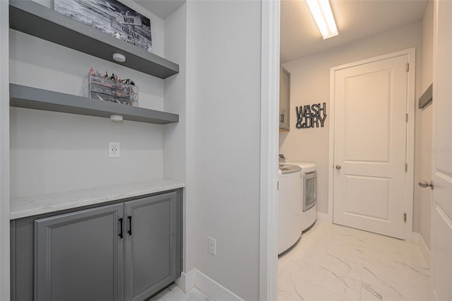 laundry area with cabinet space, baseboards, marble finish floor, and separate washer and dryer