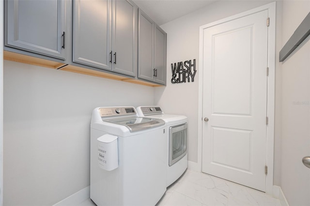 laundry area featuring cabinet space, baseboards, washing machine and dryer, and marble finish floor