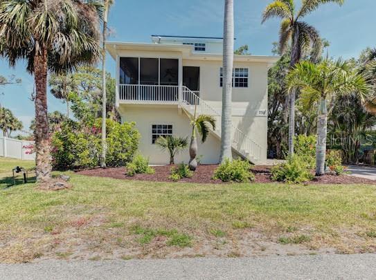 view of front of home with stairway, a front lawn, a sunroom, and stucco siding