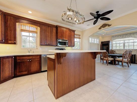kitchen with a kitchen breakfast bar, light countertops, appliances with stainless steel finishes, and crown molding
