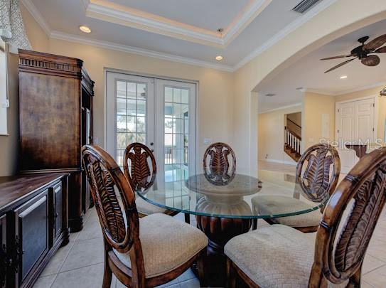 dining area with a ceiling fan, visible vents, arched walkways, and light tile patterned floors