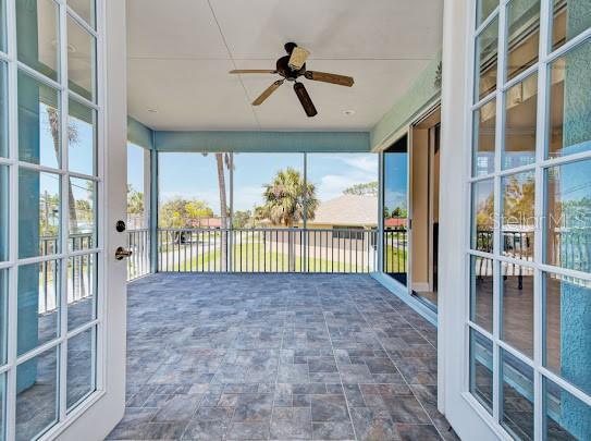 unfurnished sunroom featuring ceiling fan and stone finish floor