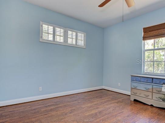 empty room with baseboards, wood finished floors, and ceiling fan