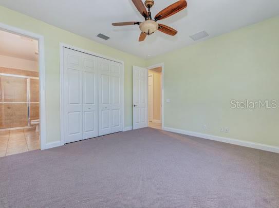 unfurnished bedroom featuring ensuite bathroom, a closet, baseboards, carpet flooring, and visible vents