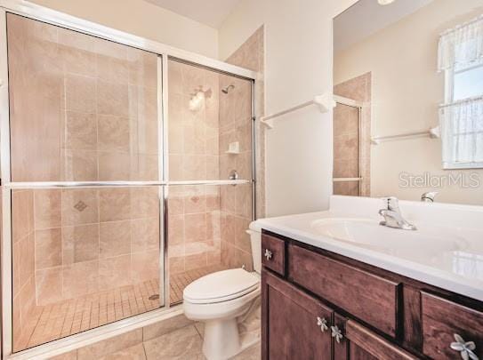 bathroom with a shower stall, toilet, vanity, and tile patterned floors