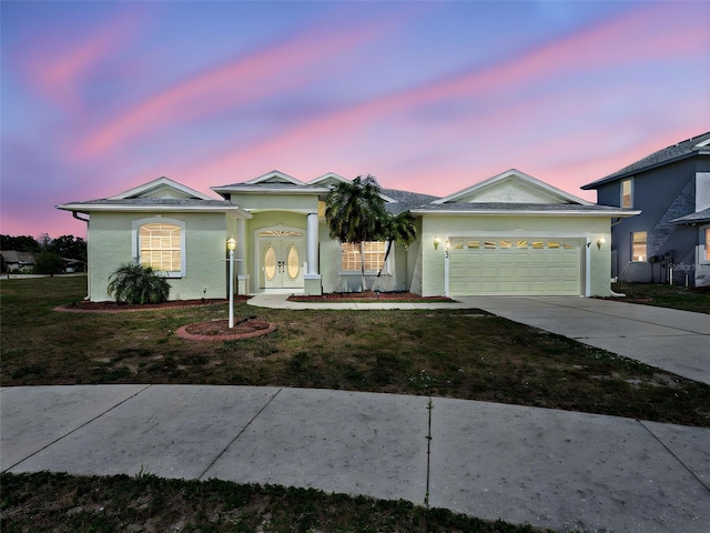 ranch-style home with a garage, concrete driveway, stucco siding, and a yard