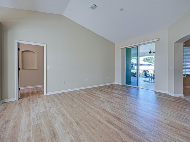 unfurnished room featuring vaulted ceiling, arched walkways, light wood finished floors, and baseboards
