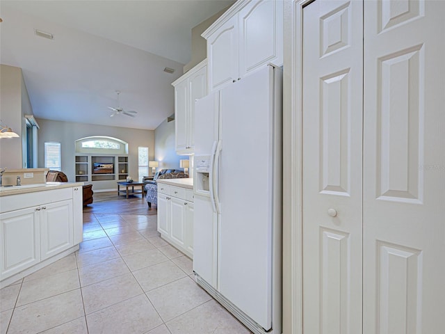 kitchen featuring white fridge with ice dispenser, a ceiling fan, light tile patterned floors, white cabinets, and open floor plan