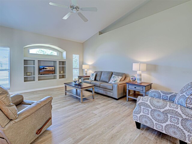living area with high vaulted ceiling, light wood finished floors, a ceiling fan, and baseboards