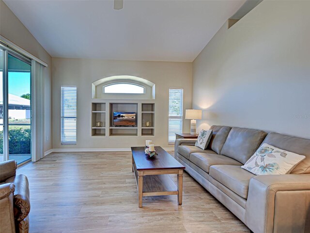 living room with light wood finished floors, plenty of natural light, vaulted ceiling, and baseboards